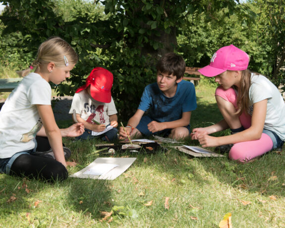 Kinder zeichnen auf einer Wiese